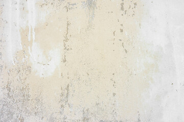 Textured beige plaster wall surface with peeling paint. Aged, weathered concrete background