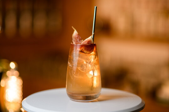 Transparent cocktail with pieces of ice and exotic fruits stands on a round white stand