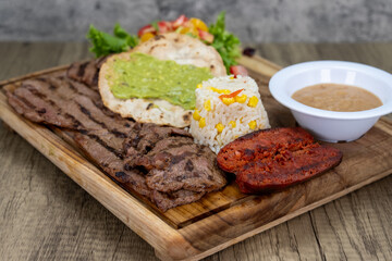 Grilled carne asada sliced meat dinner served with rice, chorizo, and beans on a wooden platter