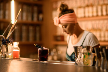 Focus on a glass with a black drink and topped with a skewer with blackberries strung on it
