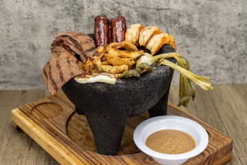 Mexican meat dinner molcajete filled with grilled carne asada, shrimp, chorizo sausage, white fish, and green onion sizzling hot for dinner