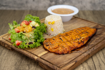 Grilled zarandeado fillet dinner served with rice and beans on a wooden platter