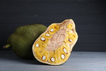 Delicious cut and whole exotic jackfruit on grey wooden table