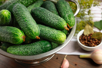 Fresh green cucumbers in colander on table, closeup