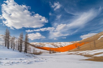 A brilliant orange hue foregrounds a snowy field, with scattered trees and rolling hills under a bright blue sky with clouds