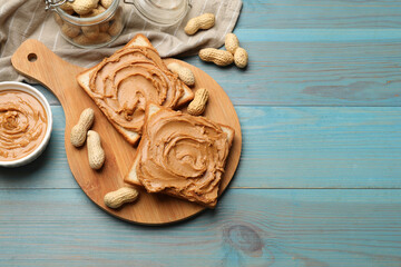 Tasty sandwiches with peanut butter and nuts on light blue wooden table, flat lay. Space for text