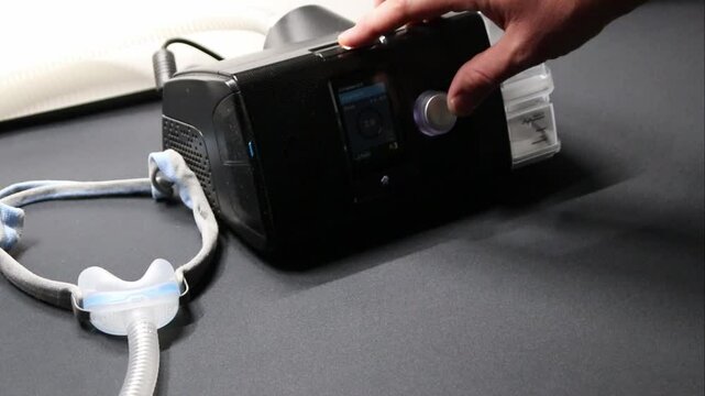 Male European with cpap machine checking therapy analysis via smartphone app or medical app for e-health check and health report via mobile device for health analysis innovative sleep apnea mask apps