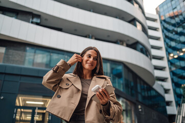 Businesswoman listening music on earbuds walking on city street