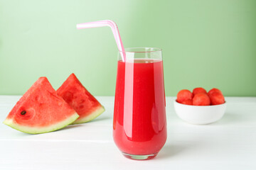 Tasty watermelon drink in glass and fresh fruit on white wooden table