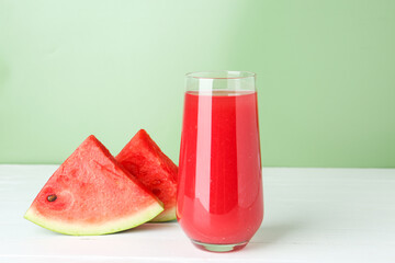 Tasty watermelon drink in glass and fresh fruit on white wooden table