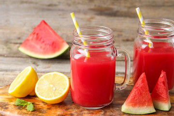 Tasty watermelon drink in mason jars and fresh fruits on wooden table, closeup
