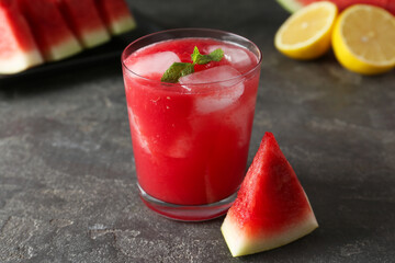 Tasty watermelon drink in glass, fresh fruits and mint on grey table, closeup