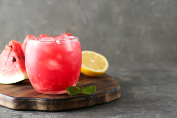 Tasty watermelon drink in glass, fresh fruits and mint on grey table, closeup. Space for text