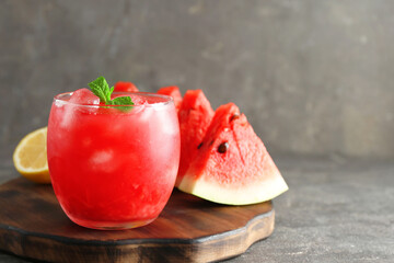 Tasty watermelon drink in glass, fresh fruits and mint on grey table, closeup