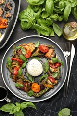 Tasty salad with grilled vegetables and mozzarella cheese served on black wooden table, flat lay