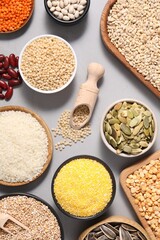 Different types of cereals, seeds and legumes on grey table, flat lay