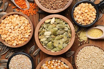 Different types of cereals, legumes and seeds on wooden table, flat lay