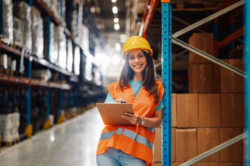 Warehouse worker smiling and holding clipboard checking inventory