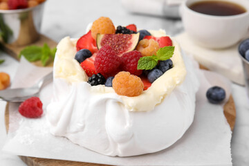 Pavlova cake (meringue dessert) with whipped cream, fresh berries, fig and mint on table, closeup