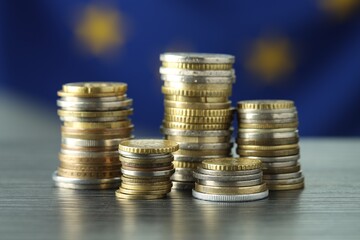 Stacks of euro coins on grey textured table, closeup