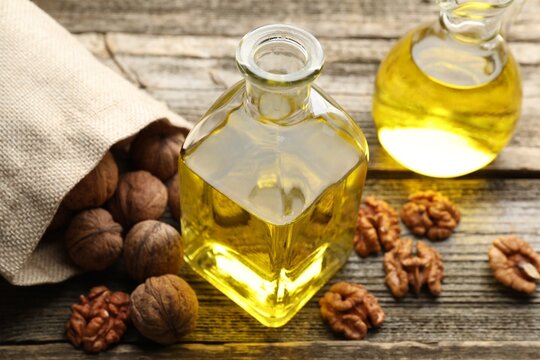 Cooking oil and walnuts on wooden table, closeup