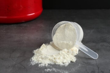 Protein powder in scoop on grey textured table