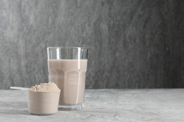 Delicious protein shake in glass and scoop with powder on grey table, space for text