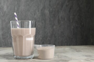 Delicious protein shake in glass and scoop with powder on grey table, space for text