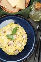 Plate with delicious pasta Carbonara, oil and cheese on grey textured table, flat lay
