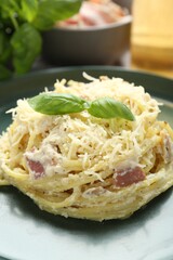 Delicious pasta Carbonara with basil on table, closeup