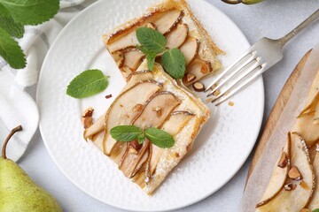 Pieces of tasty puff pastry pie with pears and mint on light grey table, top view