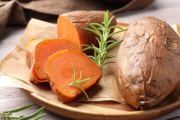 Tasty cooked sweet potatoes and rosemary on wooden table, closeup