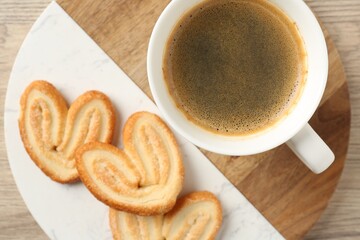 Delicious palmier cookies with coffee on wooden table, top view