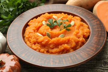 Tasty mashed sweet potato with pumpkin seeds and parsley in bowl on table, closeup