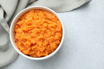 Tasty mashed sweet potato in bowl on gray table, top view. Space for text