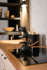 Black kettle on stovetop in a modern kitchen with warm lighting and wooden accents during evening...