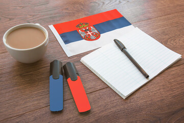 serbian national flag, cup of coffee, notebook, two markers on the desktop, foreign language...