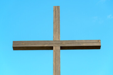Fototapeta premium An Orthodox wooden cross on a background of blue sky and clouds. An old antique cross close-up.