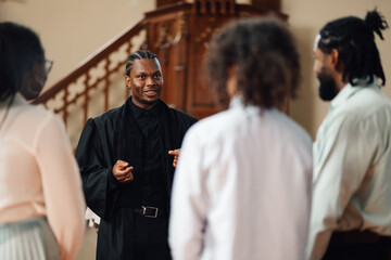 Young priest speaking to his parishioners inside the church