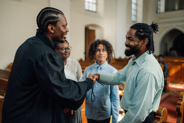 Fototapeta premium Priest giving rosary beads to young man in church