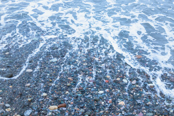 colorful pebbles beneath the foamy water on the sea shore, Black Sea, Batumi