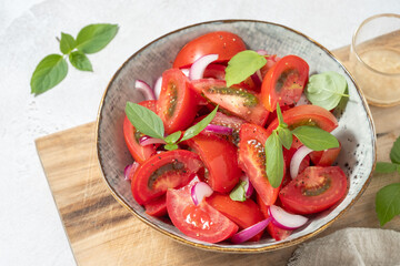 A bowl of tomatoes and onions with basil on top