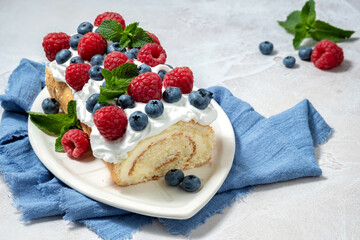 A slice of cake with blueberries and raspberries on top