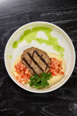 Savor a Grilled Steak served with Tomato Salsa and Green Sauce, beautifully presented