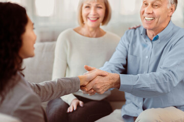Fototapeta premium Gratitude. Close up of handshake of happy mature man and female doctor greeting each other at couple therapy session