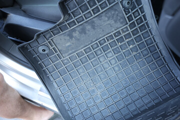Man taking black rubber car mat from auto, closeup