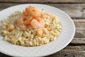 Delicious risotto with shrimps and cheese on wooden table, closeup