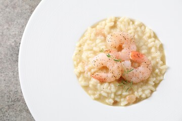 Delicious risotto with shrimps and cheese on grey table, top view