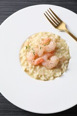 Delicious risotto with shrimps and cheese on black table, top view