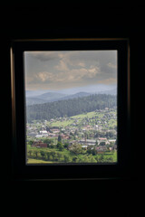 Vorokhta village view through window frame showcasing Carpathian mountains and green hills